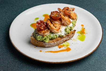 Avocado toast with shrimps and cherry tomatoes on white plateの写真素材