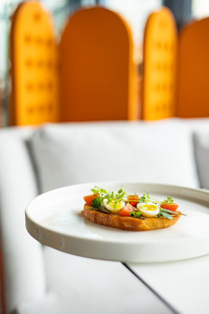 Canape with tomato and egg on a white plate in a restaurant