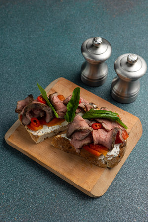 Bruschetta with roast beef and vegetables on wooden cutting boardの写真素材