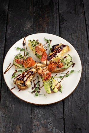 Appetizers with salmon and avocado on a white plate on a dark wooden backgroundの写真素材