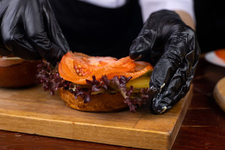 Close-up of female hands in black gloves decorating burger with salted salmonの写真素材