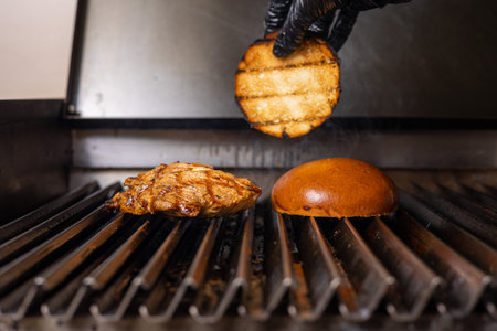 Chef cooking a hamburger on a gas grill in the kitchenの写真素材