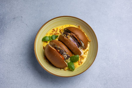 Fried eggs with sausage in a bun on a gray background.