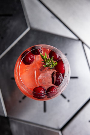 Cocktail with cranberries and rosemary on a black background