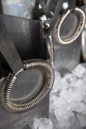 Close-up of steel cocktail shaker with ice cubes on background