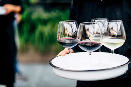 Waiter is carring plate with red Wine glasses.の写真素材