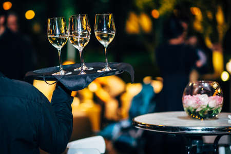 Waiter is carring plate with white Wine glasses.  Wine glasses.の写真素材