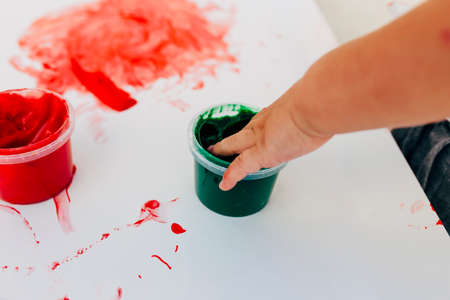 2-3 years old boys paint with hands on white paper, with bare hands, they using green, red and blue colour on white canvas paper.の写真素材