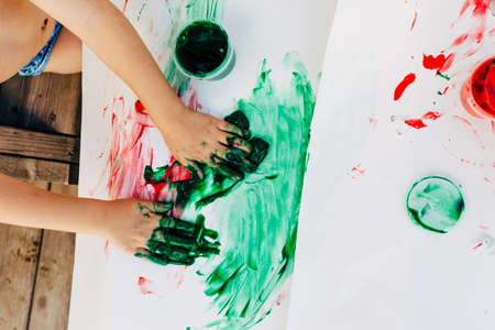 2-3 years old boys paint with hands on white paper, with bare hands, they using green, red and blue colour on white canvas paper.の写真素材