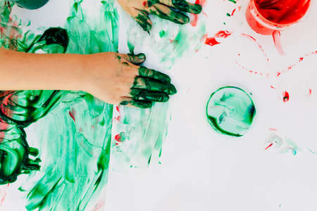 2-3 years old boys paint with hands on white paper, with bare hands, they using green, red and blue colour on white canvas paper.の写真素材