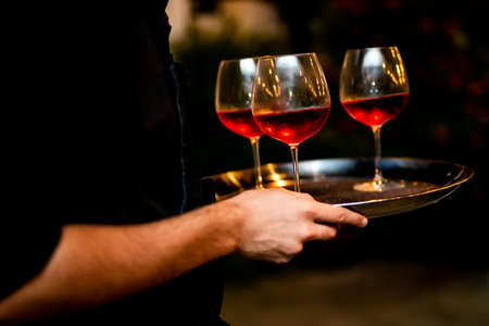 waiter is holding glass of red and white wine. fancy and luxury events.の写真素材
