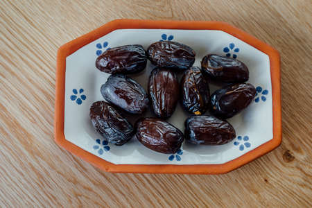 Dates in a plate on wooden surface