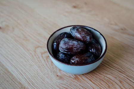 Dates in a bowl on wooden surfaceの写真素材