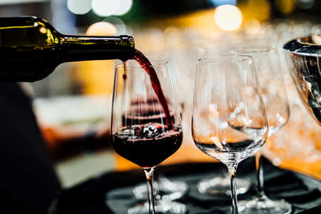 Man is pouring red or white wine in social event like weddings business gathering or romantic dinner.の写真素材