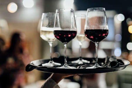 Man is pouring red or white wine in social event like weddings business gathering or romantic...