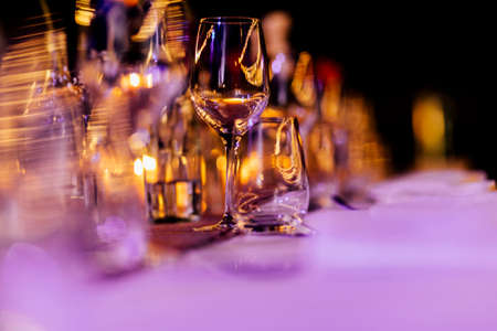 Luxury table settings for fine dining with and glassware, pouring wine to glass. Beautiful blurred background. Preparation for holiday wedding. Fancy luxury restaurant.の写真素材