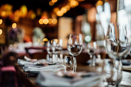 Luxury table settings for fine dining with and glassware, pouring wine to glass. Beautiful blurred background. Preparation for holiday wedding. Fancy luxury restaurant.の写真素材