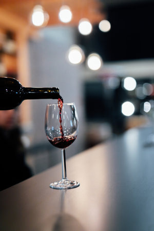 Red wine being poured into a glass on a bar counter in a restaurant