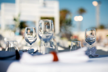 Luxury table settings for fine dining with and glassware, pouring wine to glass. Beautiful blurred background. Preparation for holiday wedding. Fancy luxury restaurant.の写真素材