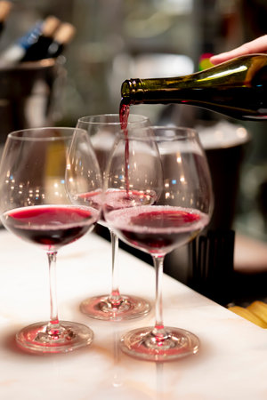 Pouring  redcwine at luxury restaurant and luxuryy tabel settings. elegant light and dishes.の写真素材