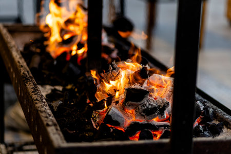 burning charcoal barbecue grill, fire burning in a evening blue light as a preparation to meat and fish meal outdoors. 2024 content.の写真素材