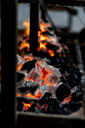 burning charcoal barbecue grill, fire burning in a evening blue light as a preparation to meat and fish meal outdoors. 2024 content.の写真素材