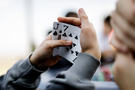 Detailed shot of hands shuffling poker chips and holding playing cards during a high-stakes game. The vibrant colors of the chips and the crisp textures of the cards emphasize the energy and tension of the momentの写真素材