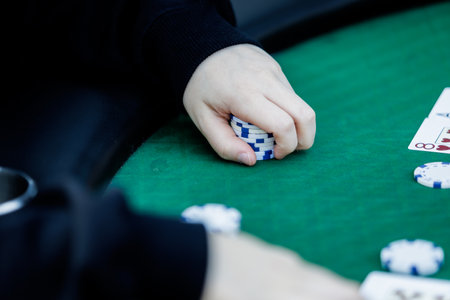 Detailed shot of hands shuffling poker chips and holding playing cards during a high-stakes game. The vibrant colors of the chips and the crisp textures of the cards emphasize the energy and tension of the momentの写真素材