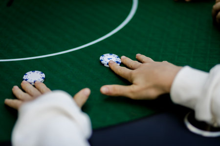 Detailed shot of hands shuffling poker chips and holding playing cards during a high-stakes game. The vibrant colors of the chips and the crisp textures of the cards emphasize the energy and tension of the momentの写真素材