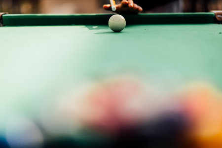 A pool table with scattered billiard balls, a cue stick, and accessories captured in a dynamic,...