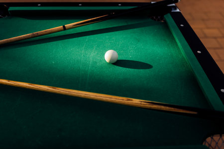 A pool table with scattered billiard balls, a cue stick, and accessories captured in a dynamic, game-ready scene. The detailed focus on the equipment highlights the timeless appeal of billiards as both a sport and a leisure activityの写真素材
