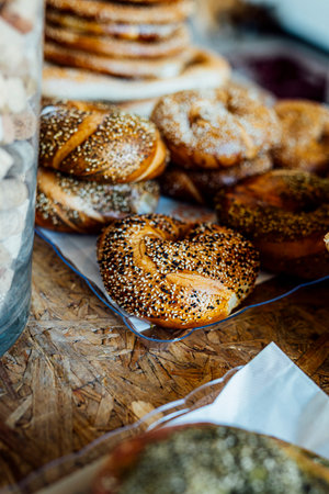 A close-up of freshly baked sesame bagels arranged in a traditional wicker basket. The golden brown crust is generously sprinkled with sesame seeds, creating a crunchy texture. The background is softly blurred, adding a rustic and artisanal feel to the image. Perfect for concepts related to bakery, breakfast, traditional food, and Middle Eastern cuisine.の写真素材