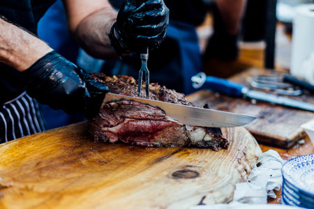 Juicy smoked beef brisket being freshly sliced on a wooden cutting board during a barbecue event. Close-up of tender meat with a charred crust, captured in natural light for a rustic and authentic culinary feel.âの写真素材
