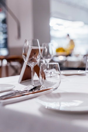 Romantically set dinner table with wine glasses and floral centerpiece, perfect for a wedding, elegant party, or outdoor evening celebration. Warm lights and soft bokeh create an intimate and luxurious atmosphere.の写真素材