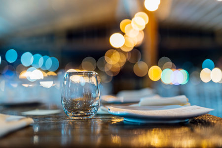 Romantically set dinner table with wine glasses and floral centerpiece, perfect for a wedding, elegant party, or outdoor evening celebration. Warm lights and soft bokeh create an intimate and luxurious atmosphere.の写真素材