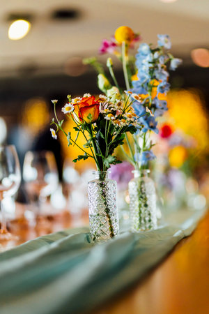 Romantically set dinner table with wine glasses and floral centerpiece, perfect for a wedding, elegant party, or outdoor evening celebration. Warm lights and soft bokeh create an intimate and luxurious atmosphere.の写真素材