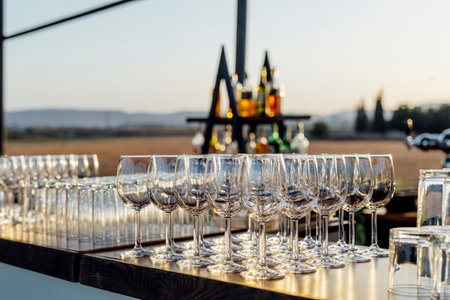 Romantically set dinner table with wine glasses and floral centerpiece, perfect for a wedding, elegant party, or outdoor evening celebration. Warm lights and soft bokeh create an intimate and luxurious atmosphere.の写真素材