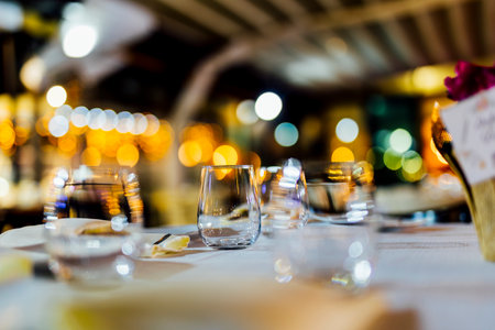 Romantically set dinner table with wine glasses and floral centerpiece, perfect for a wedding,...