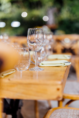 Romantically set dinner table with wine glasses and floral centerpiece, perfect for a wedding,...