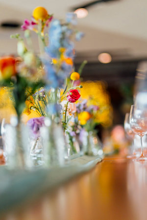 Romantically set dinner table with wine glasses and floral centerpiece, perfect for a wedding, elegant party, or outdoor evening celebration. Warm lights and soft bokeh create an intimate and luxurious atmosphere.の写真素材