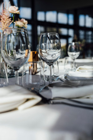An elegant table setting with cutlery, wine glasses, and white napkins, illuminated by soft natural light. Perfect for interior design, events, or hospitality concepts.の写真素材