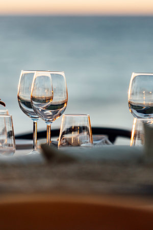 An elegant table setting with cutlery, wine glasses, and white napkins, illuminated by soft natural light. Perfect for interior design, events, or hospitality concepts.の写真素材