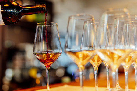 Elegant Christmas table setting with wine glasses and warm golden bokeh lights in a cozy atmosphere.の写真素材