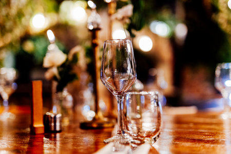 Elegant Christmas table setting with wine glasses and warm golden bokeh lights in a cozy restaurant atmosphere."の写真素材