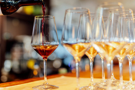 Elegant table setting with wine glasses and warm golden bokeh lights in a cozy atmosphere.の写真素材