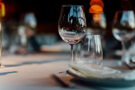 Elegant Christmas table setting with wine glasses and warm golden bokeh lights in a cozy restaurant atmosphere."の写真素材