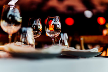 Elegant Christmas table setting with wine glasses and warm golden bokeh lights in a cozy restaurant atmosphere."の写真素材
