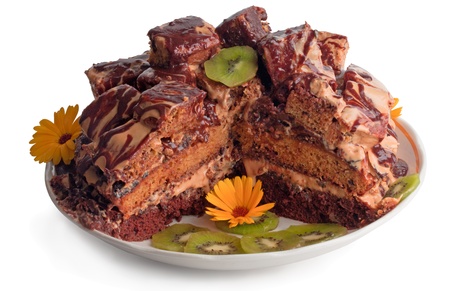 The slice of dark chocolate cake like ruins with sweet chocolate syrup and decorated with sliced kiwi and flowersの写真素材