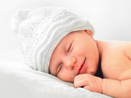 smiling european newborn baby in white hatの写真素材