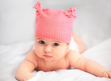 baby girl in pink hat looking at camera close upの写真素材